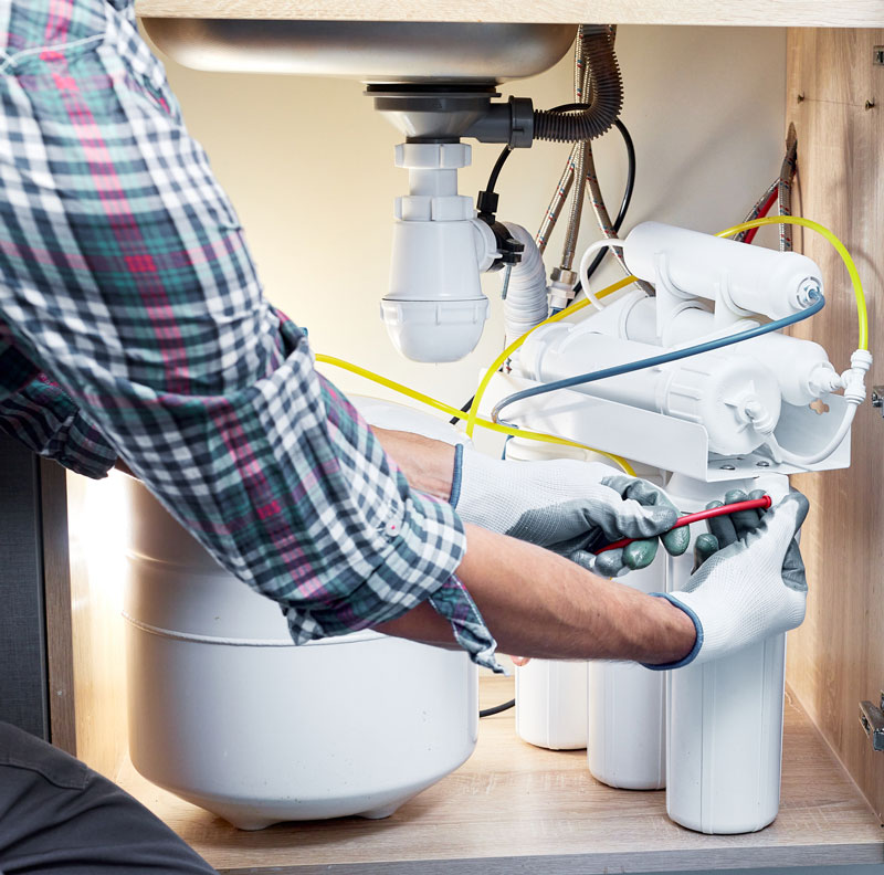 Plumber installing a reverse osmosis water filtration system.