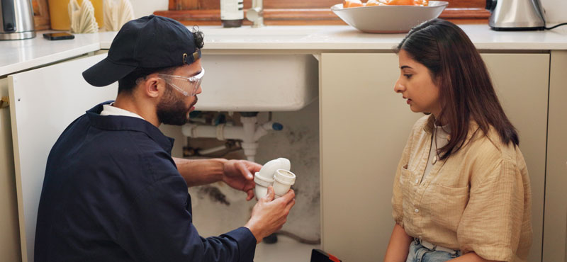 Plumber in residential home explaining an issue to the homeowner.