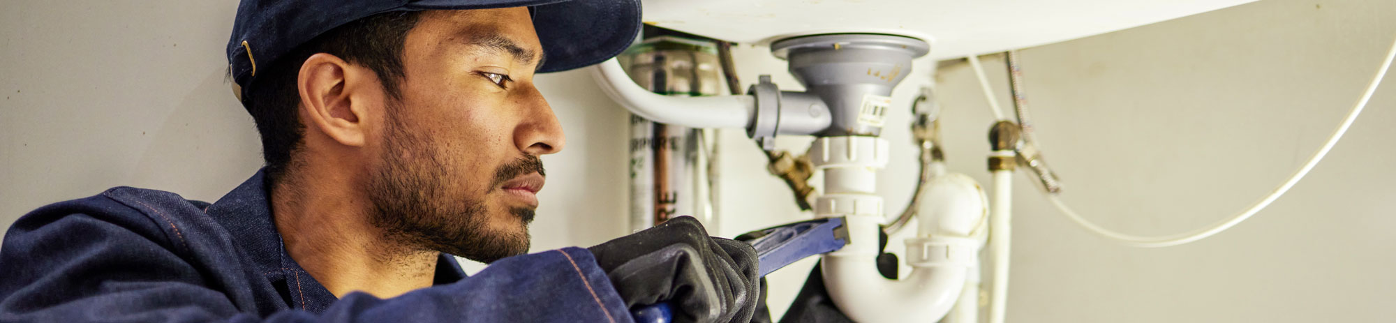 plumbing pipes and maintenance with man in kitchen