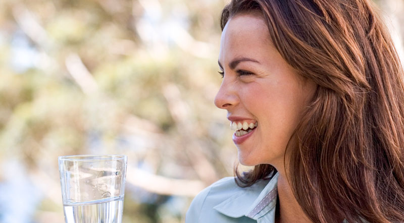 Woman drinking a glass of filtered water.